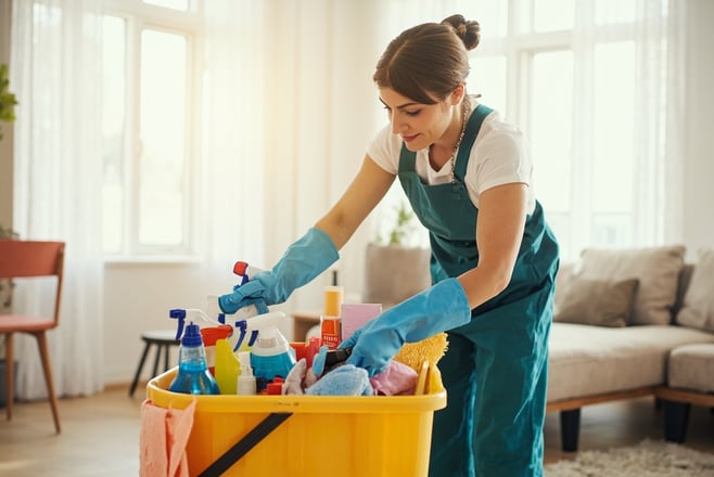 professional cleaner cleaning living room with cleaning caddy and supplies
